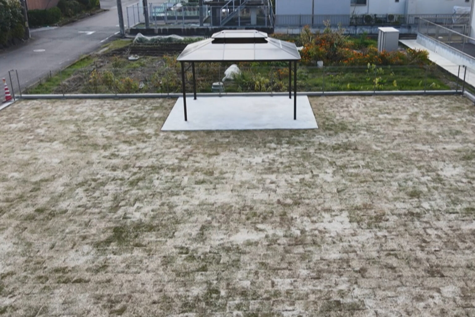 介護施設の屋上庭園。砂地にテント日よけと植栽がある入居者向けの屋外スペース。